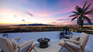 Rooftop view deck with lounge chairs and a palm tree overlooking the Las Vegas Valley at sunset